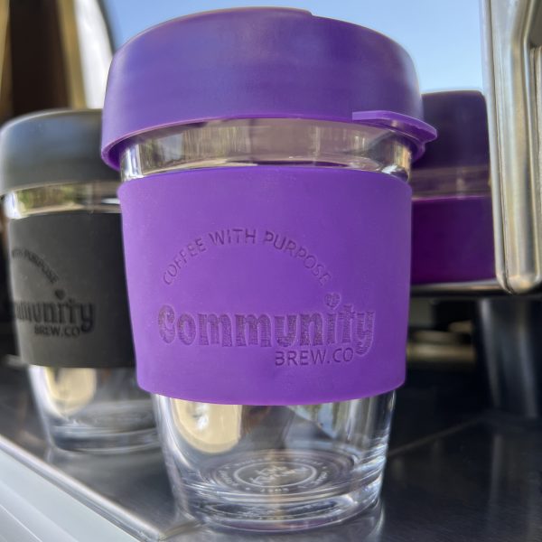 Close up of purple keep-cup with branded silicon sleeve and lid